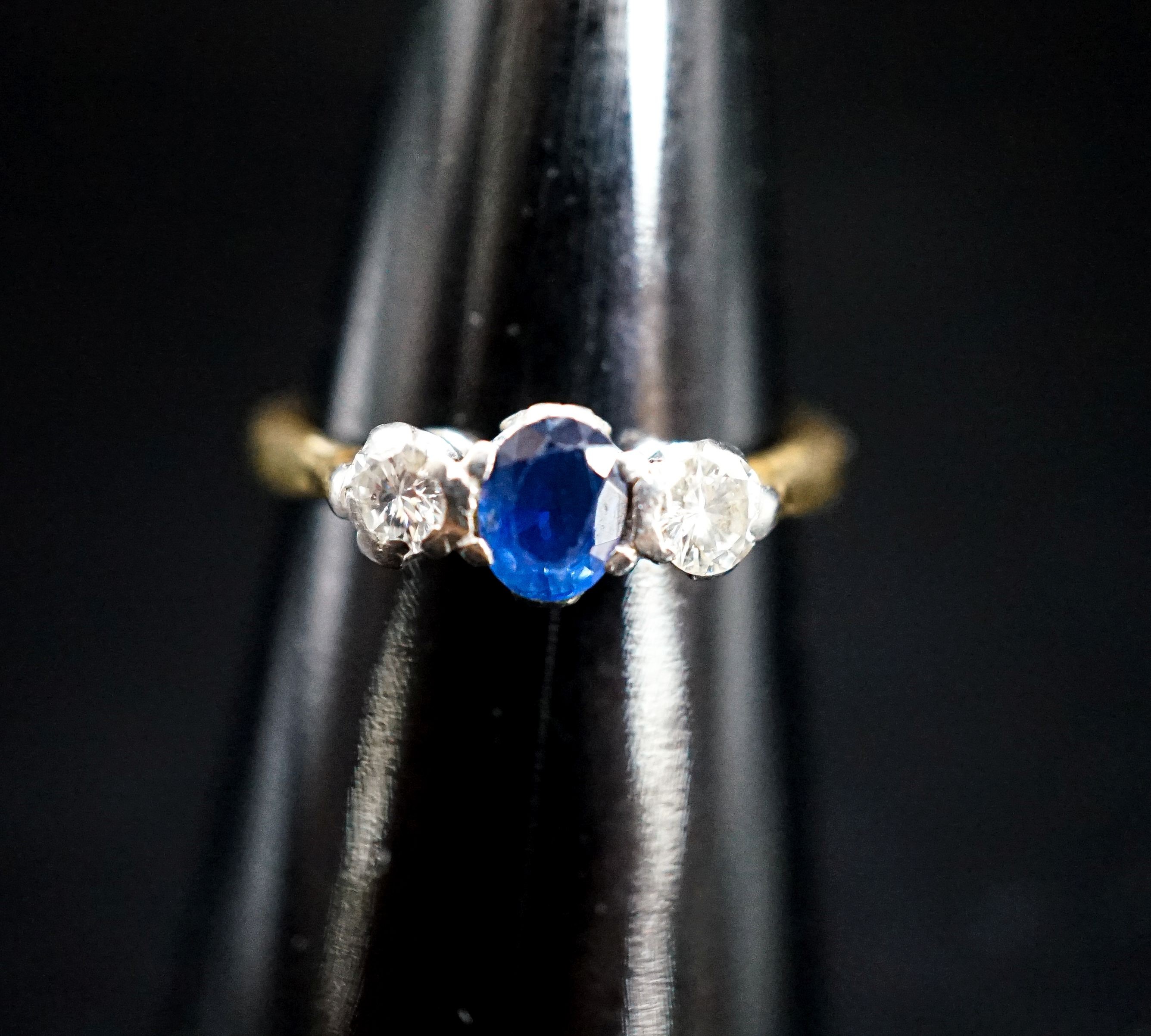 A modern 18ct gold, sapphire and diamond set three stone ring, size L/M, gross 3 grams.